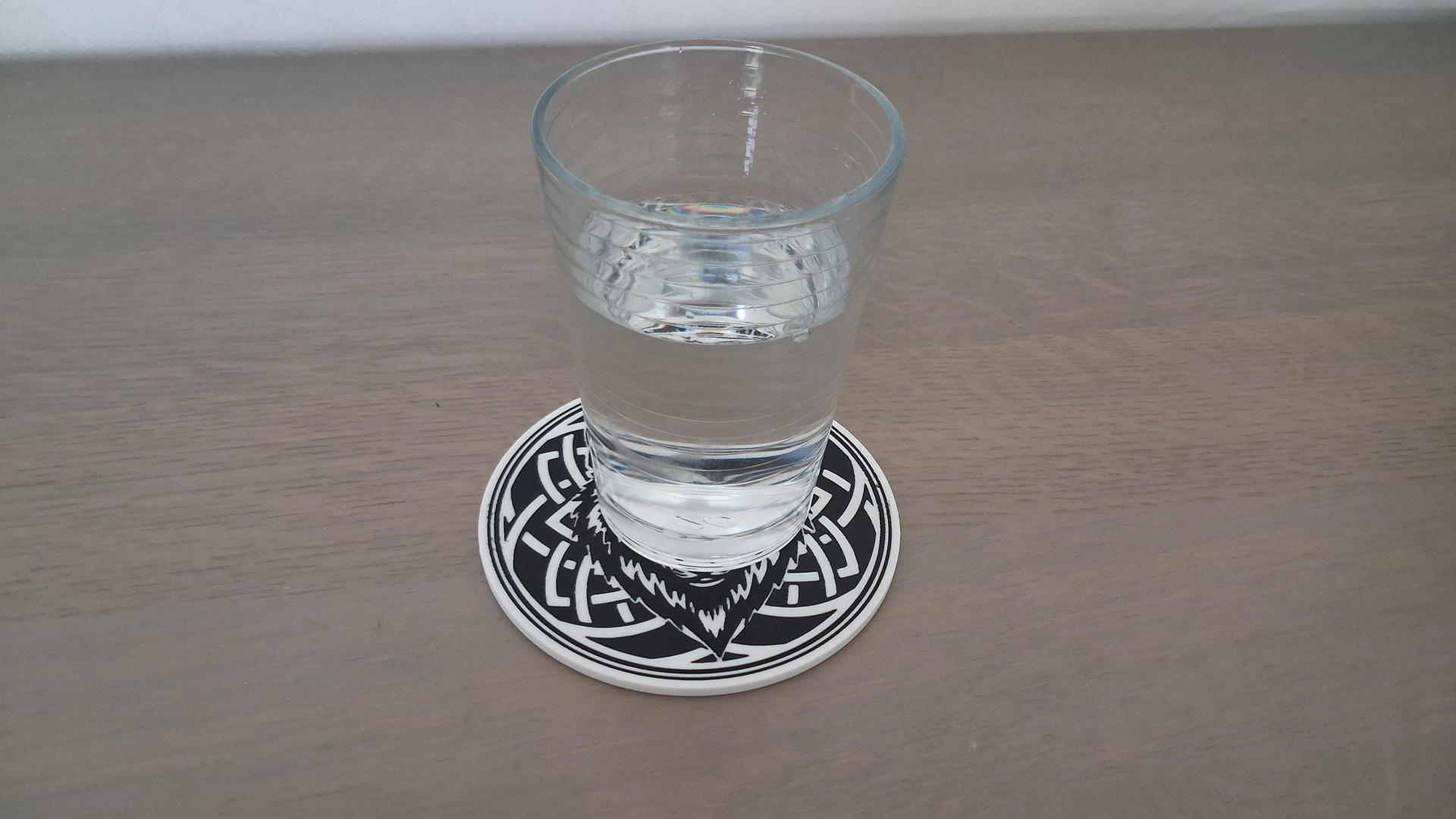 waterglas op een glasonderzetter met een wolfhoofd in zwart-wit